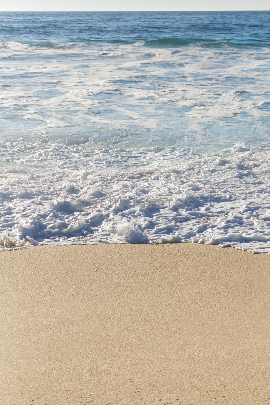 Ocean waves with white foam on a sunny day background
