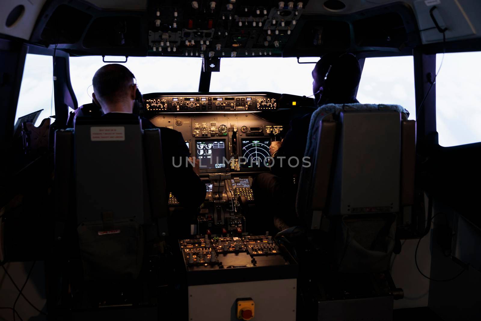 Diverse team of aircrew members using control command to fly plane in aircraft cockpit, pushing power buttons on dashboard. Captain and pilot doing teamwork flying airplane with engine lever.