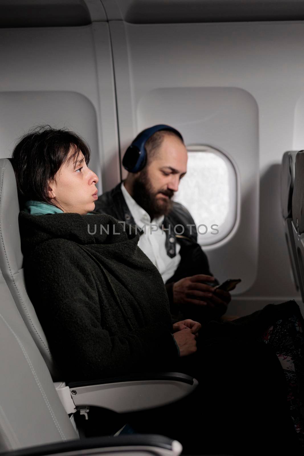 Female passenger feeling tense and scared about airplane takeoff by DCStudio