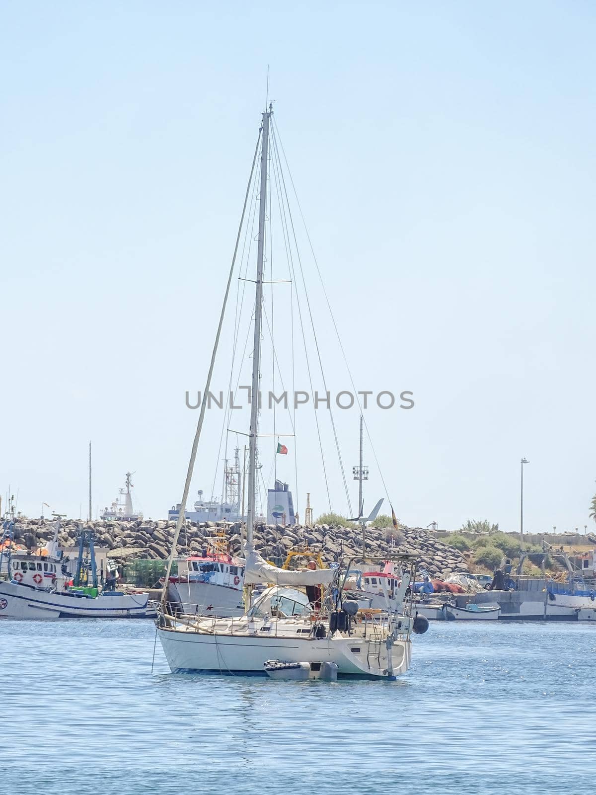 Yachts in the bay near the embankment with a lighthouse on a sunny day