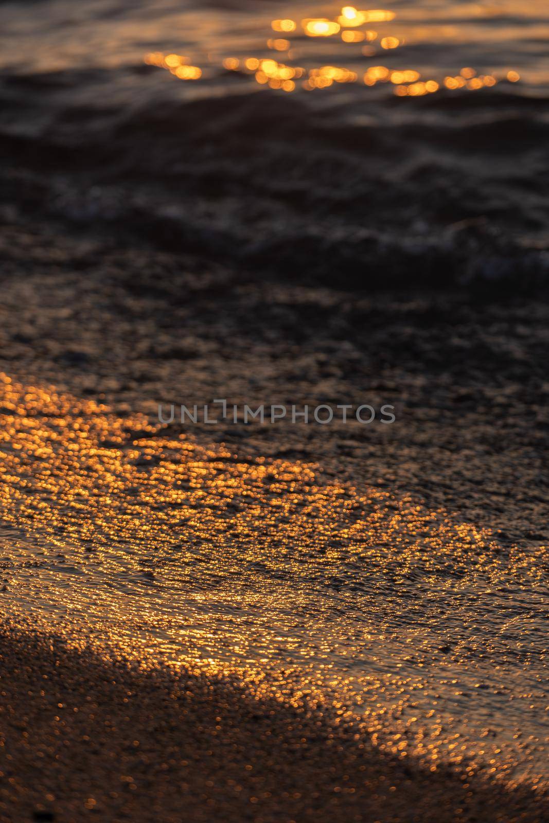 Ripple sea ocean water surface with golden sunset light. Sea waves close up