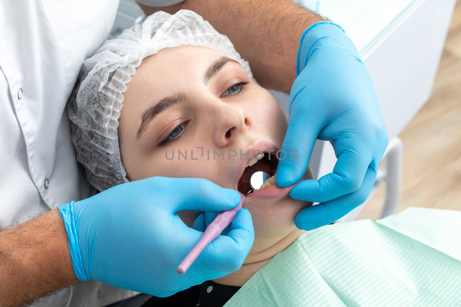 Male dentist looks at a jaw of female patient checking the bite by Mariakray