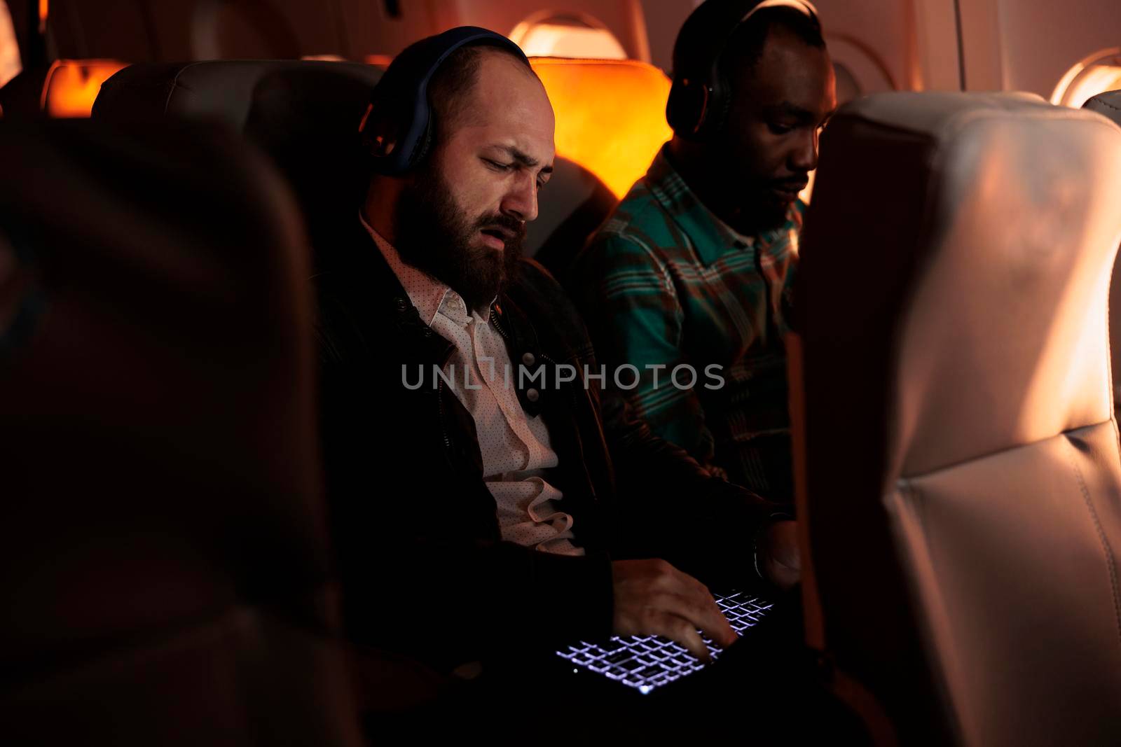 Multiethnic tourists sitting in airplane on commercial flight by DCStudio
