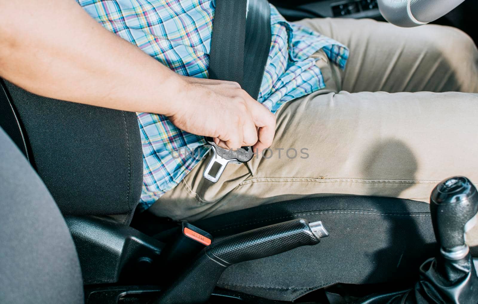 Close up of person hands putting on the seat belt. Close up of driver hands fastening the seat belt, Driver's hands putting on the seat belt. Safety belt for accident prevention by isaiphoto