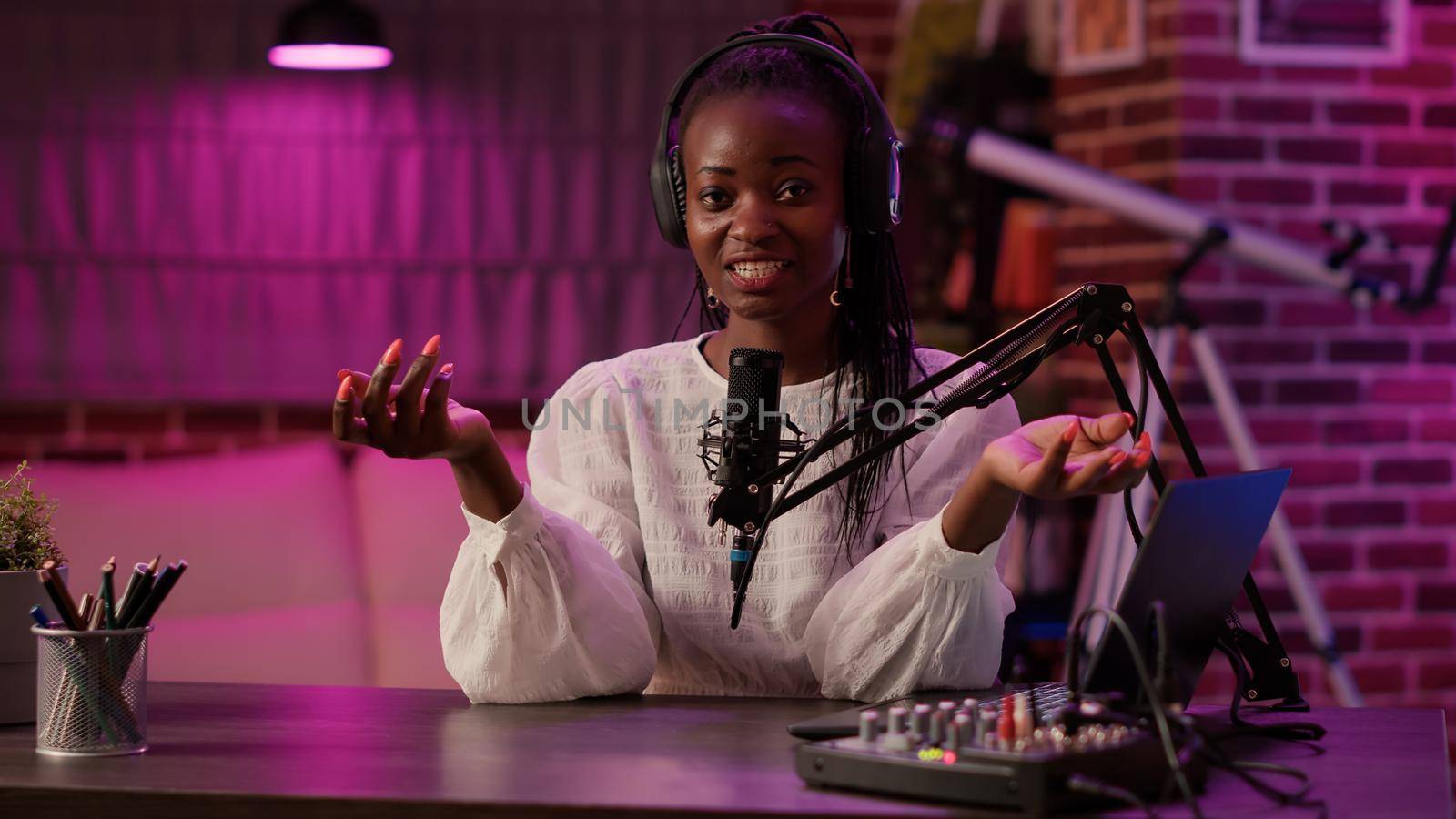 African american woman vlogger talking to audience while recording podcast using audio mixer and microphone. Famous influencer creating content for online social media page from podcasting studio.