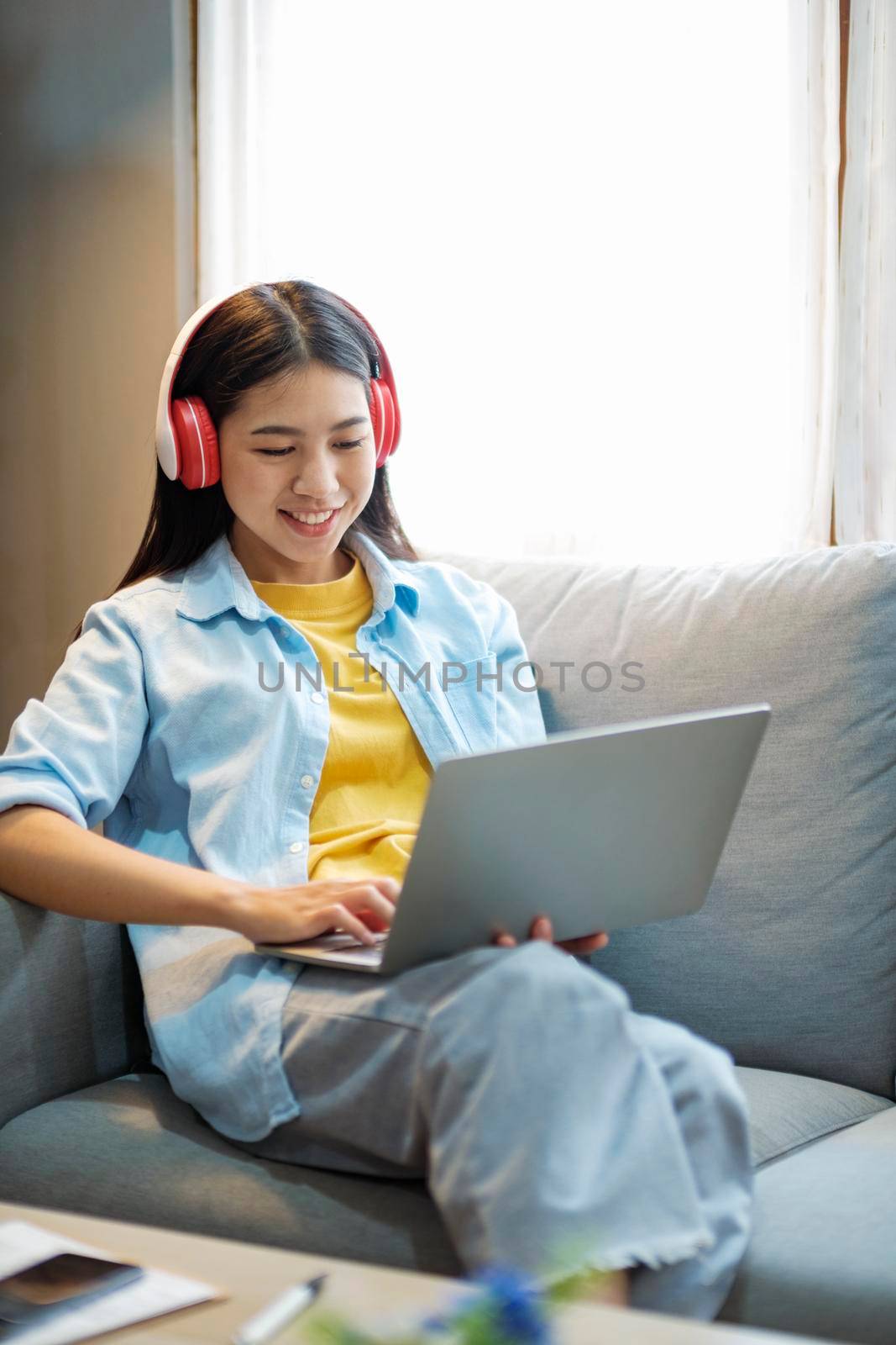 Young asian woman smiling listening to music using smartphone at home. by ijeab