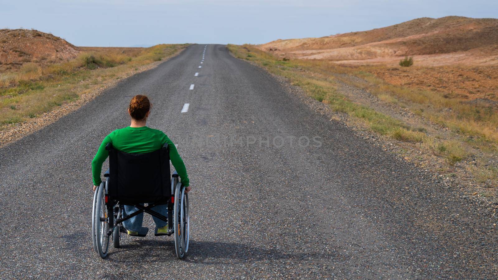 Woman in a wheelchair on a highway in the steppes