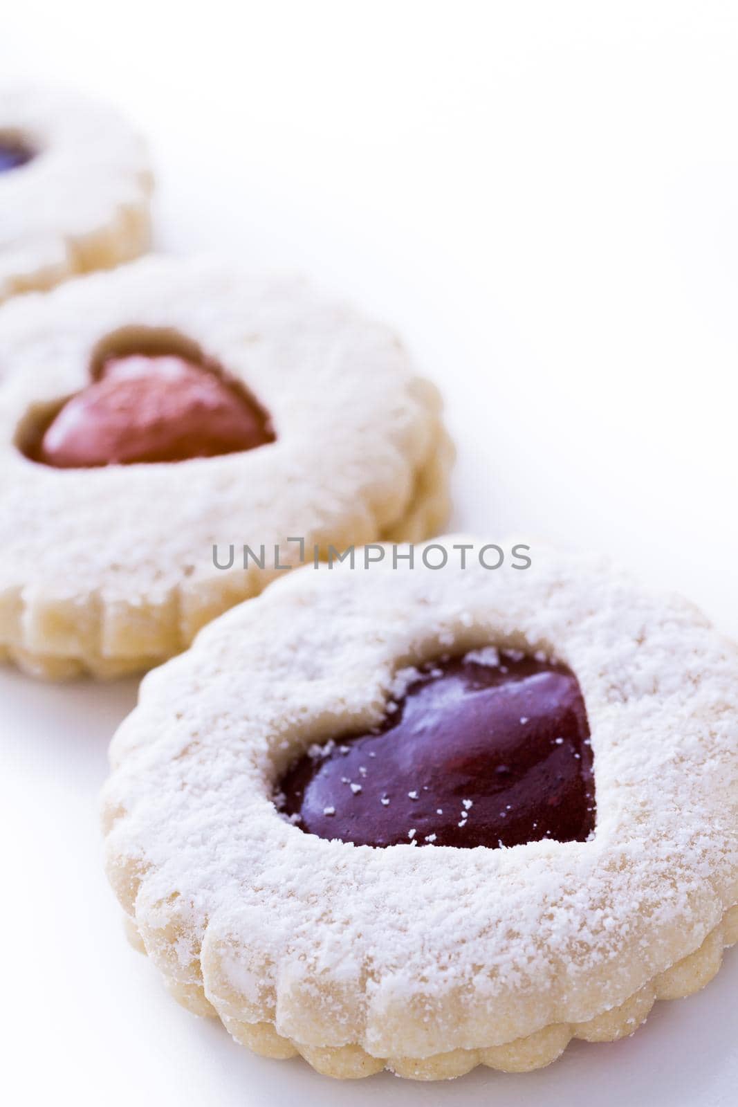 Linzer Torte cookies on white background with powdered sugar sprinkled on top.