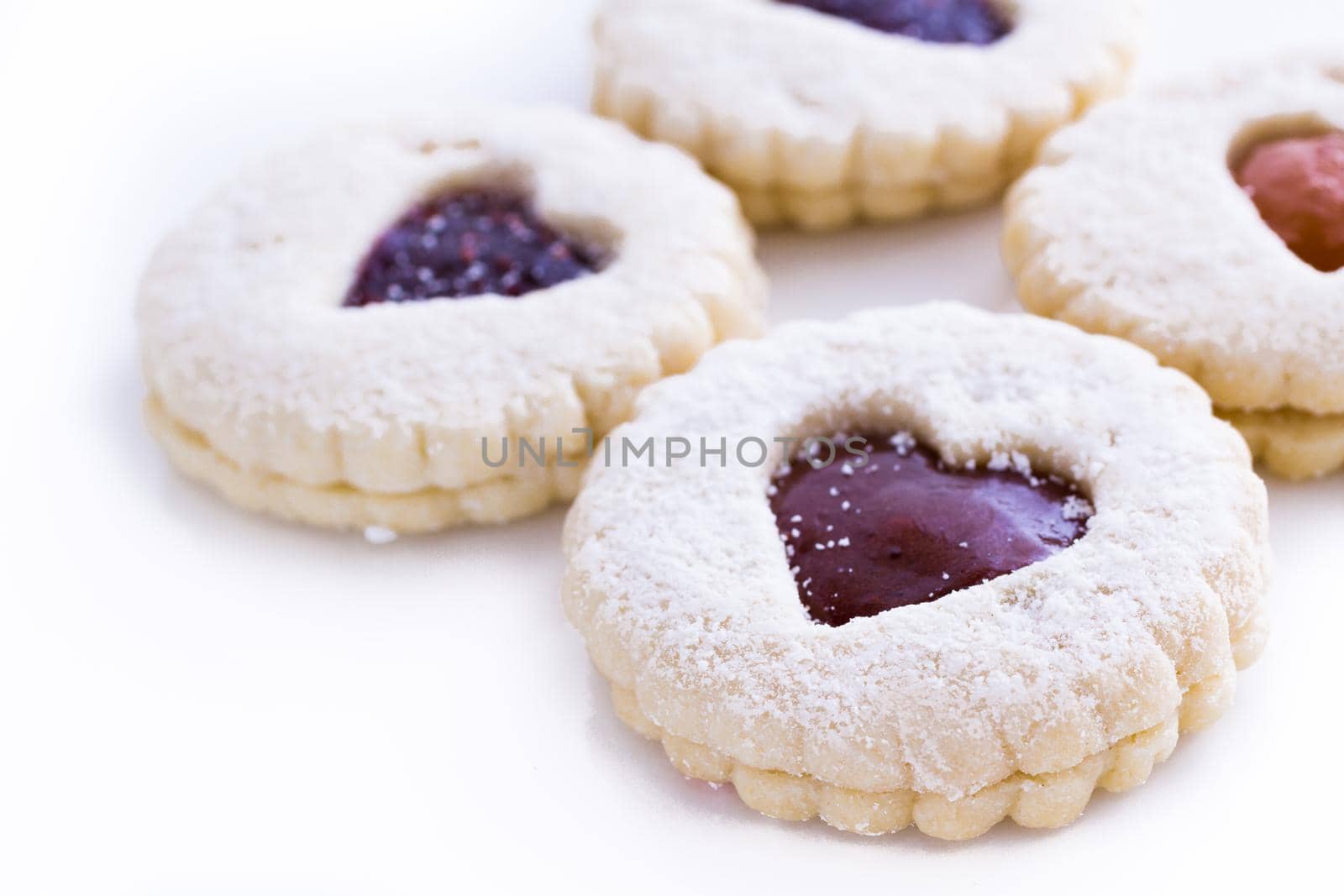 Linzer Torte cookies on white background with powdered sugar sprinkled on top.