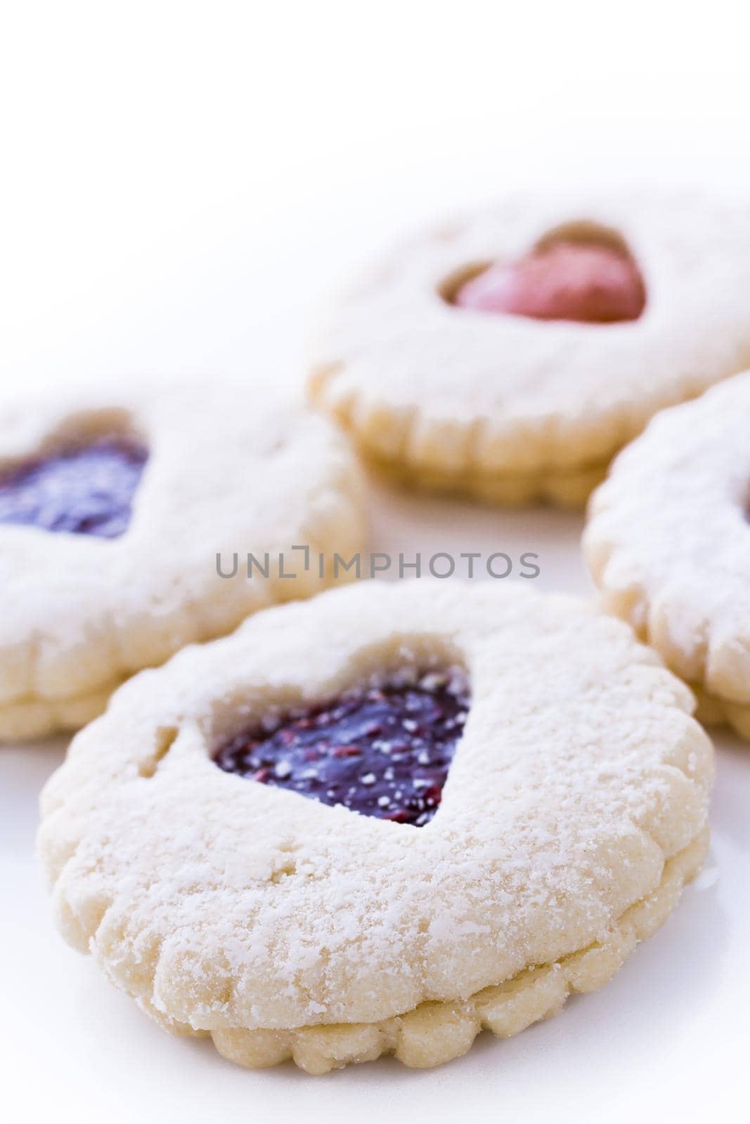 Linzer Torte cookies on white background with powdered sugar sprinkled on top.