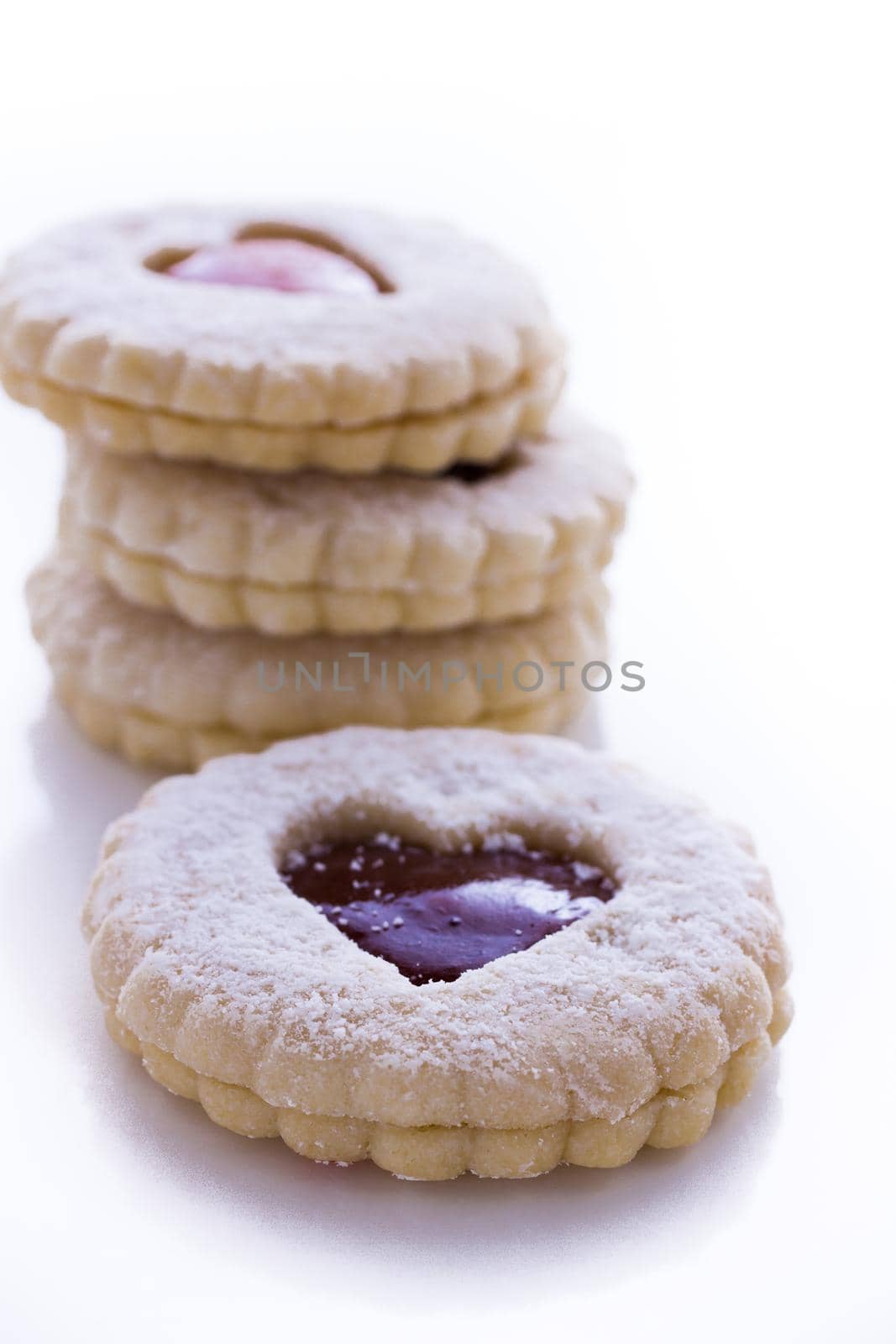 Linzer Torte cookies on white background with powdered sugar sprinkled on top.