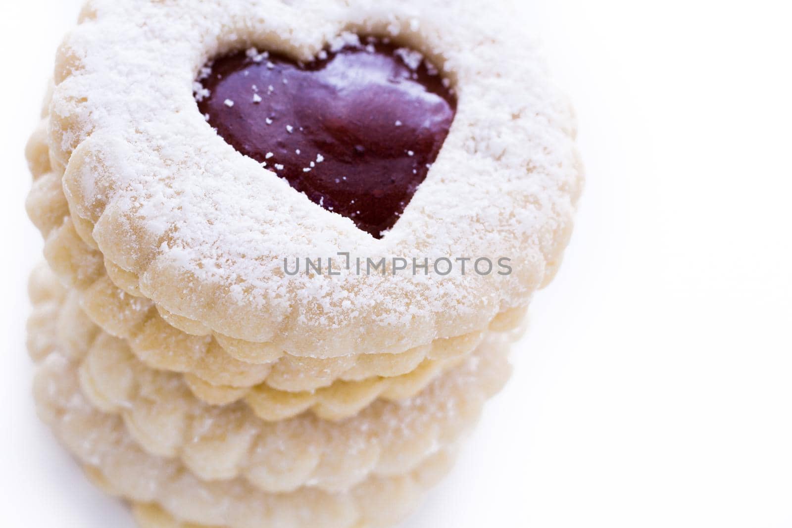 Linzer Torte cookies on white background with powdered sugar sprinkled on top.