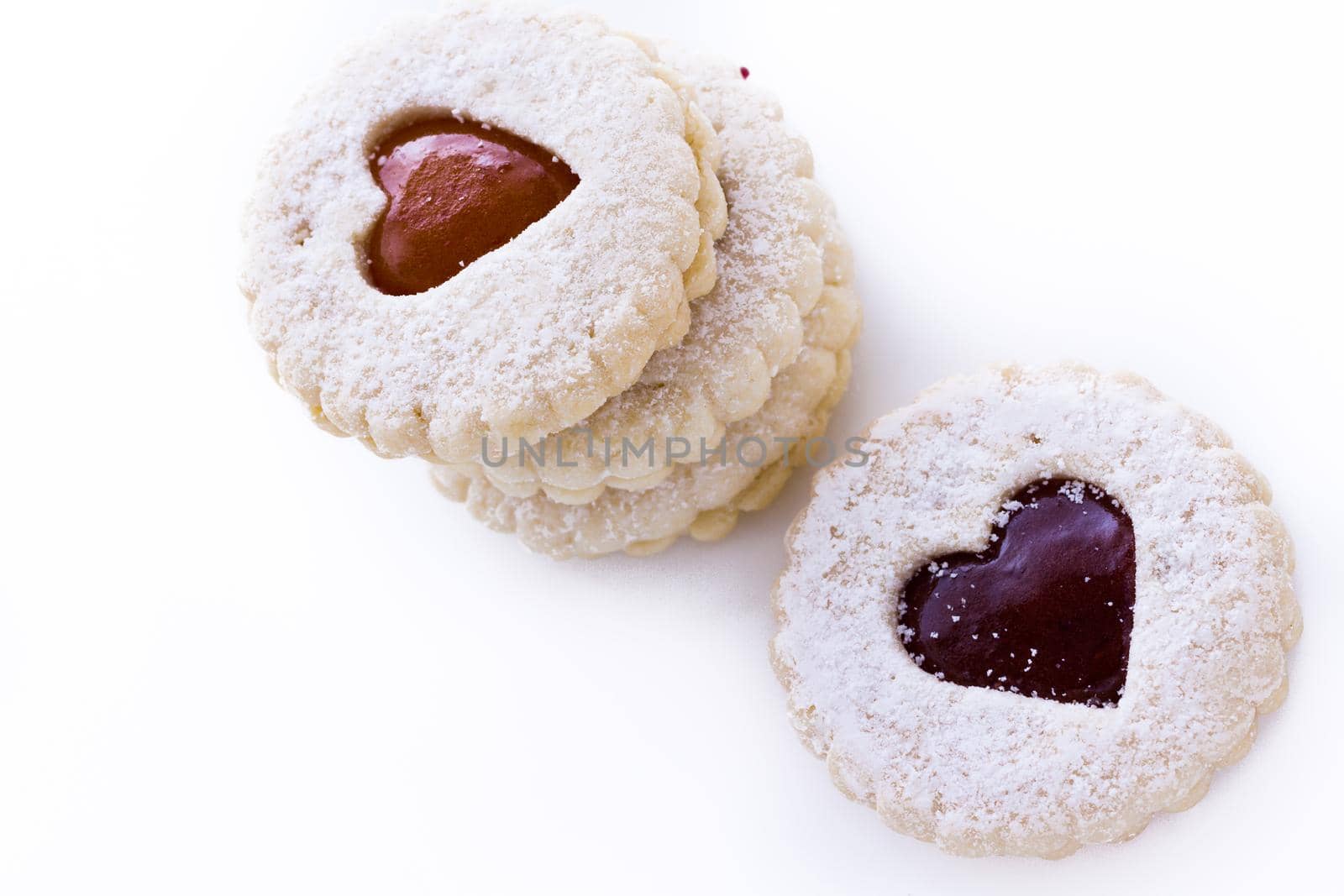 Linzer Torte cookies on white background with powdered sugar sprinkled on top.