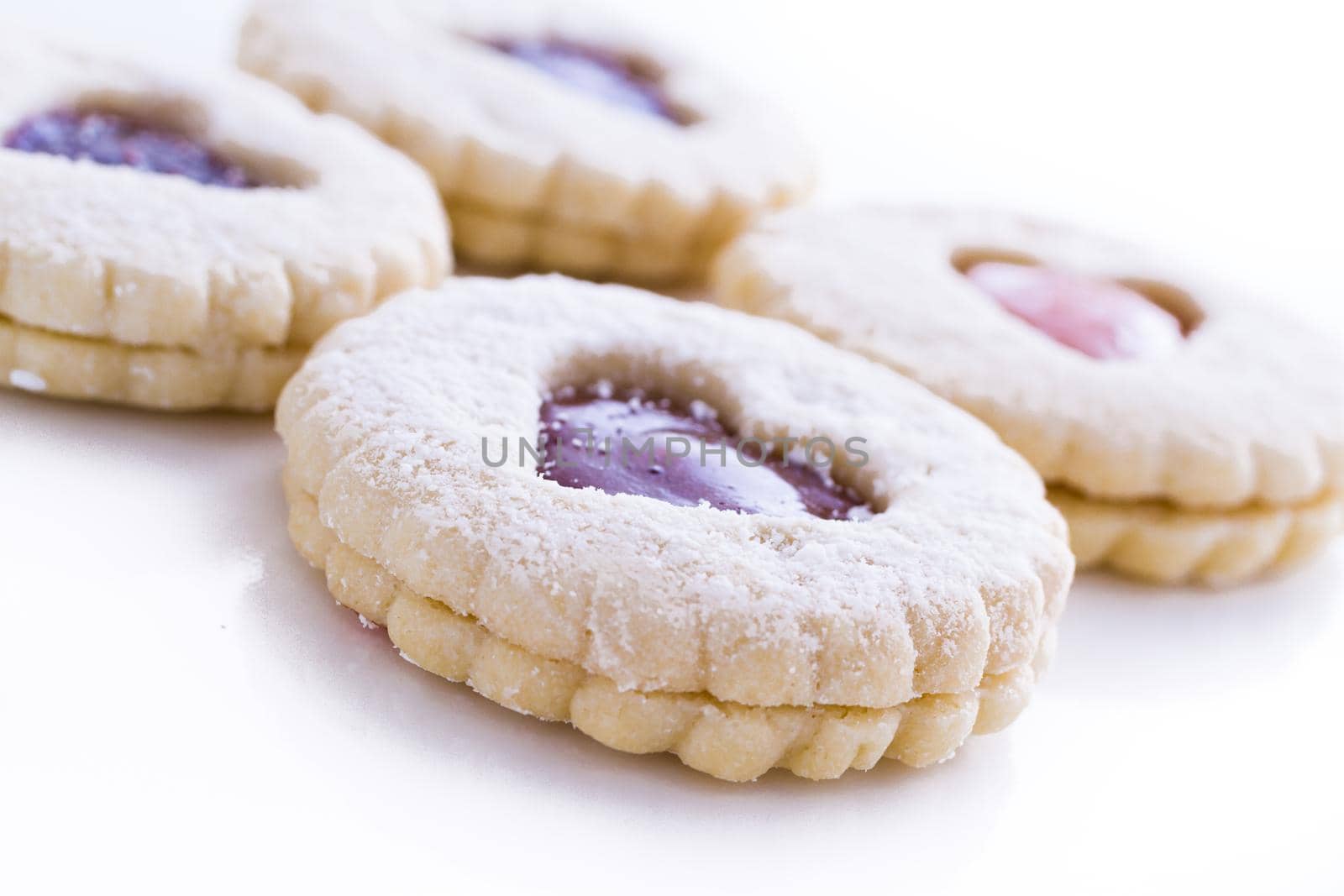 Linzer Torte cookies on white background with powdered sugar sprinkled on top.