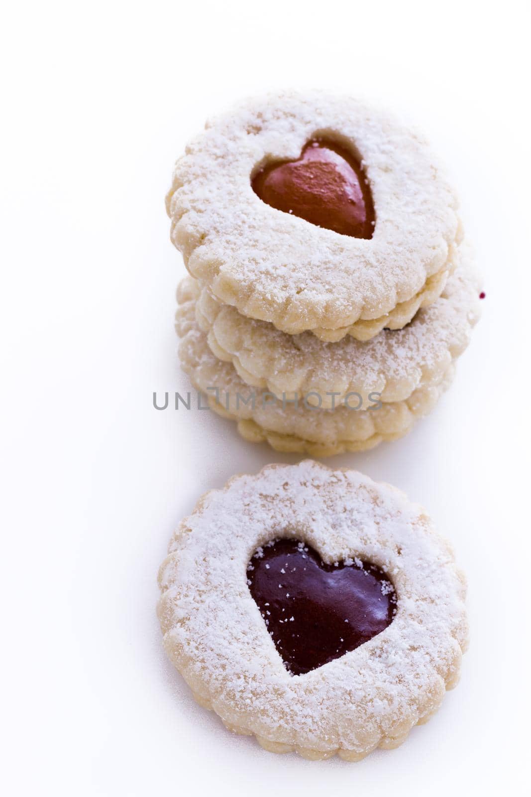 Linzer Torte cookies on white background with powdered sugar sprinkled on top.