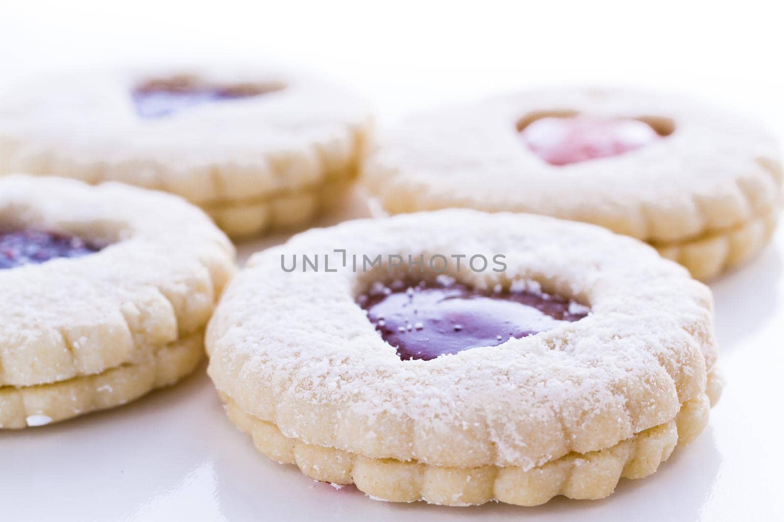 Linzer Torte cookies on white background with powdered sugar sprinkled on top.