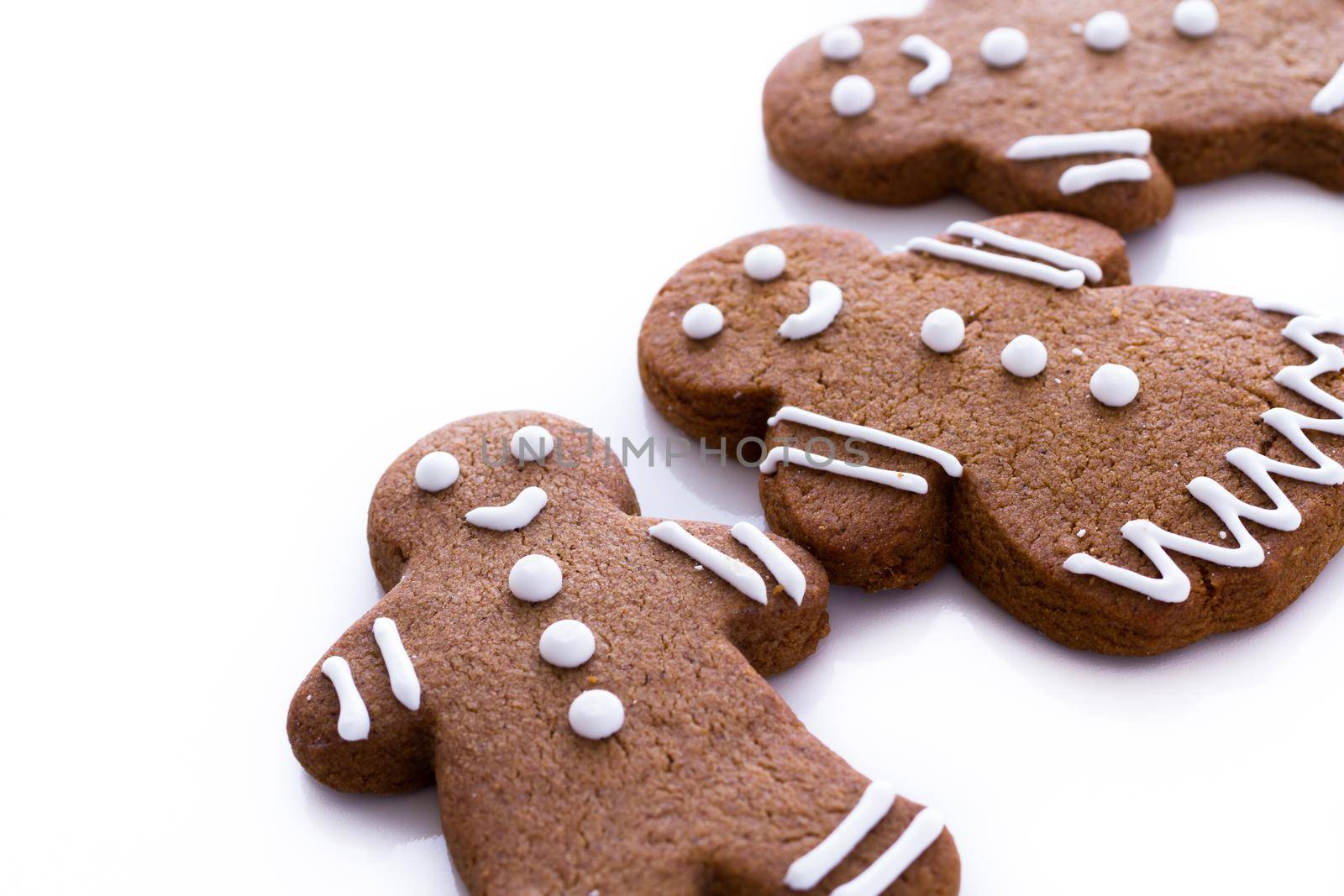 Homemade gingerbread cookies decorated with white icing on white background.