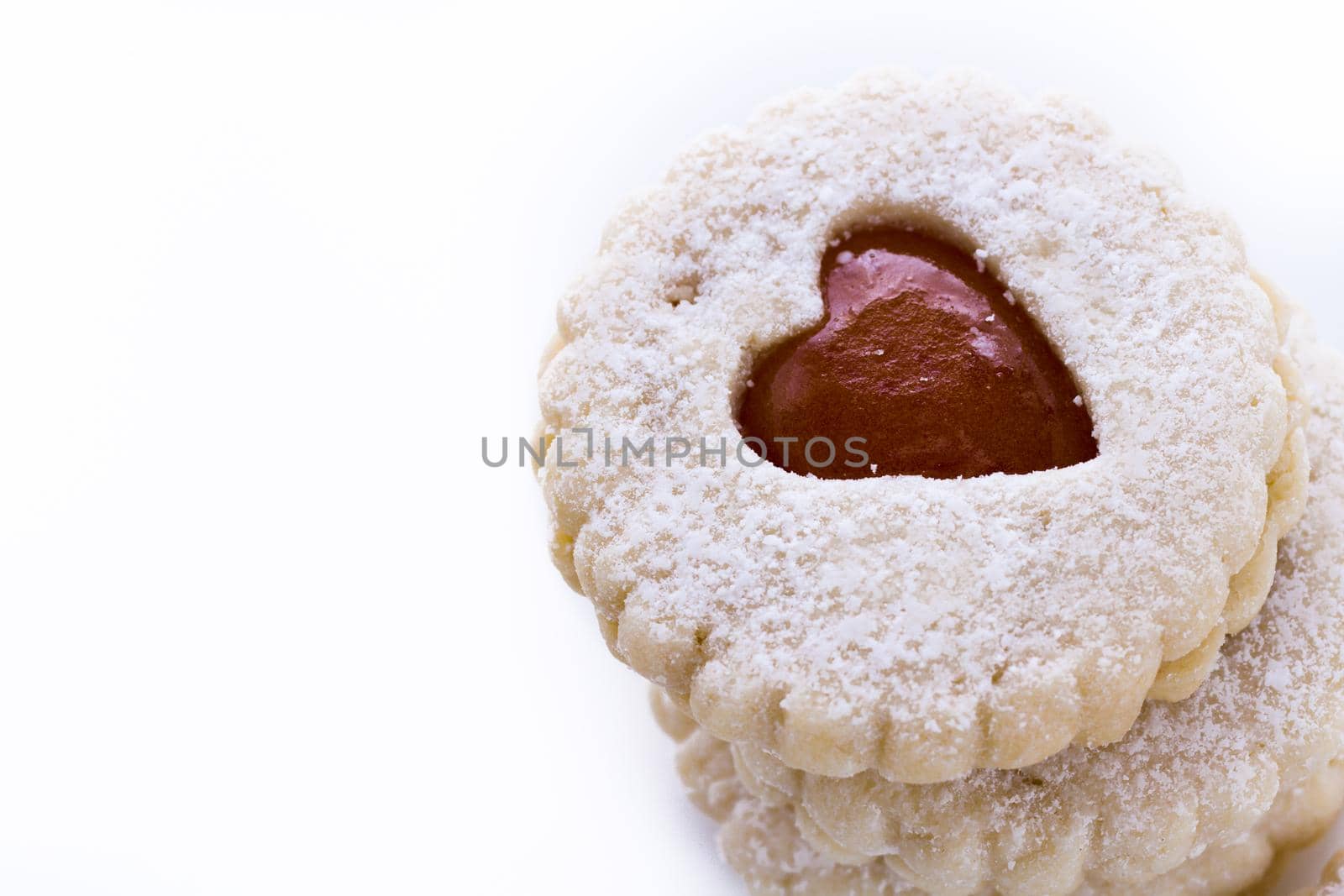 Linzer Torte cookies on white background with powdered sugar sprinkled on top.