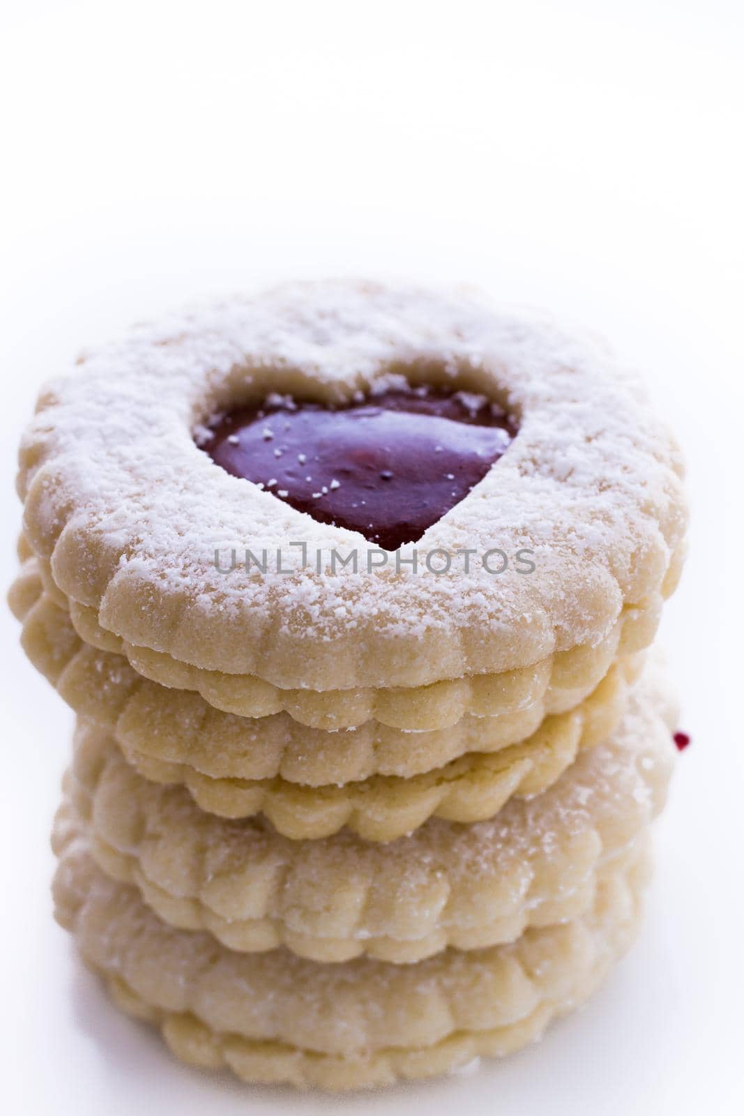 Linzer Torte cookies on white background with powdered sugar sprinkled on top.