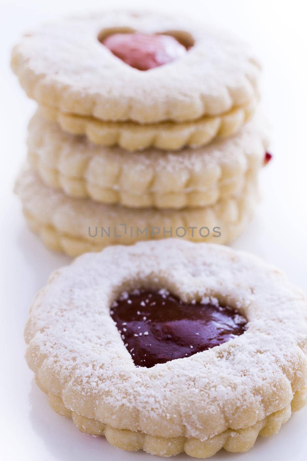 Linzer Torte cookies on white background with powdered sugar sprinkled on top.