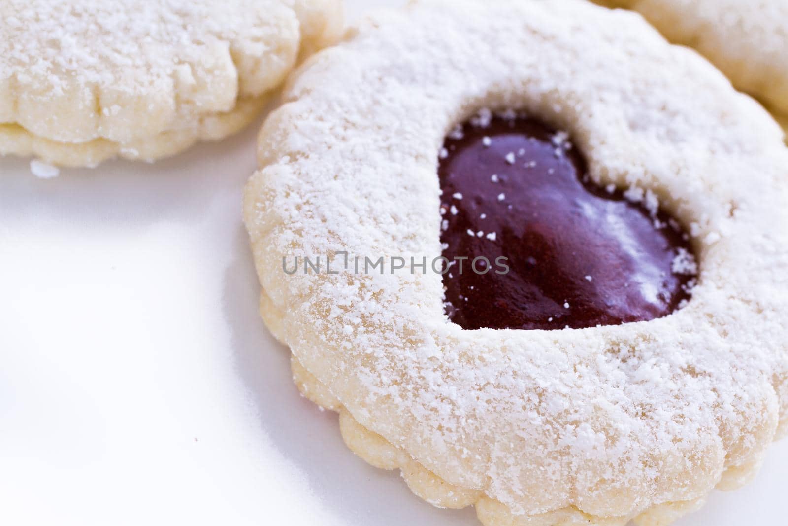 Linzer Torte cookies on white background with powdered sugar sprinkled on top.