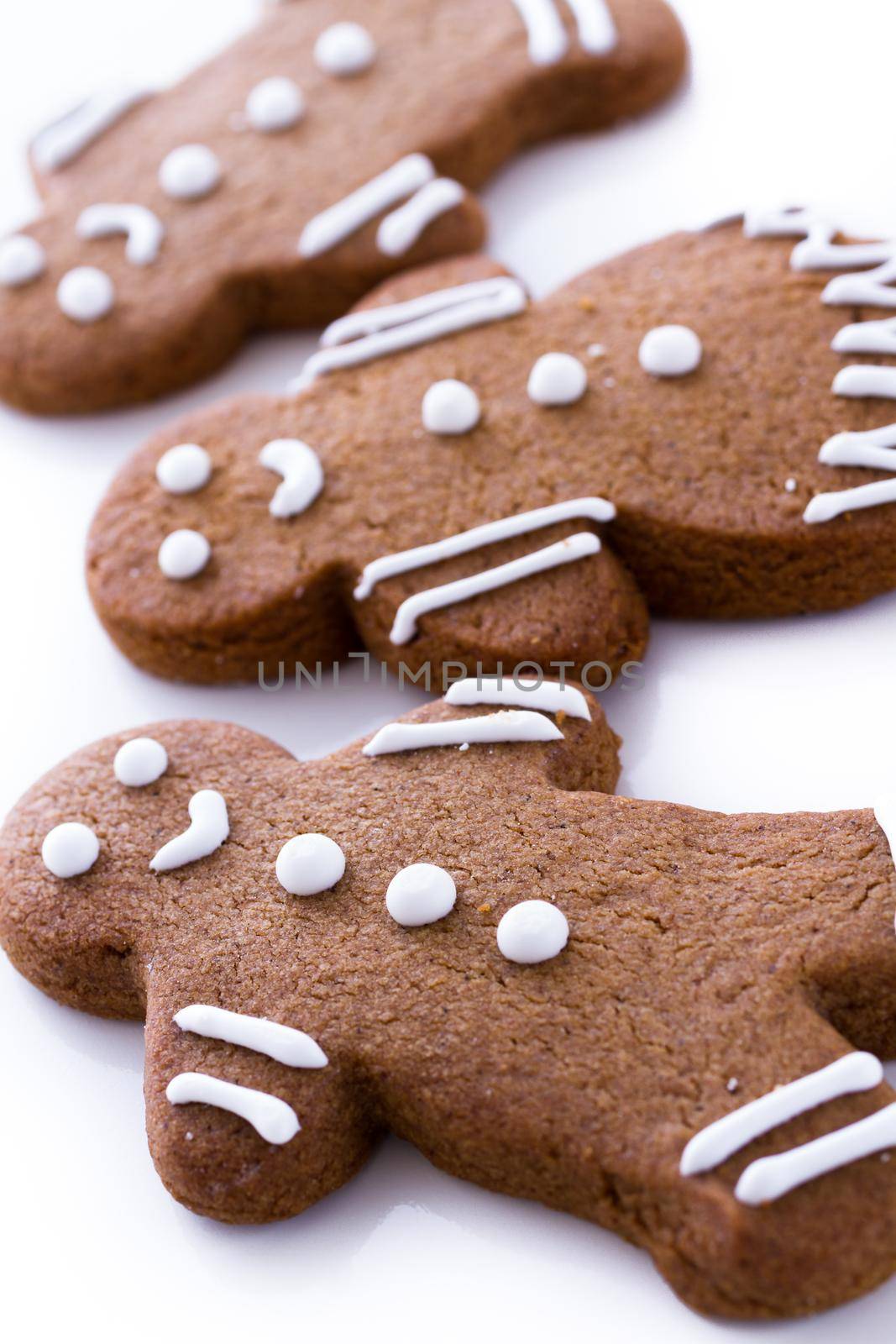 Homemade gingerbread cookies decorated with white icing on white background.