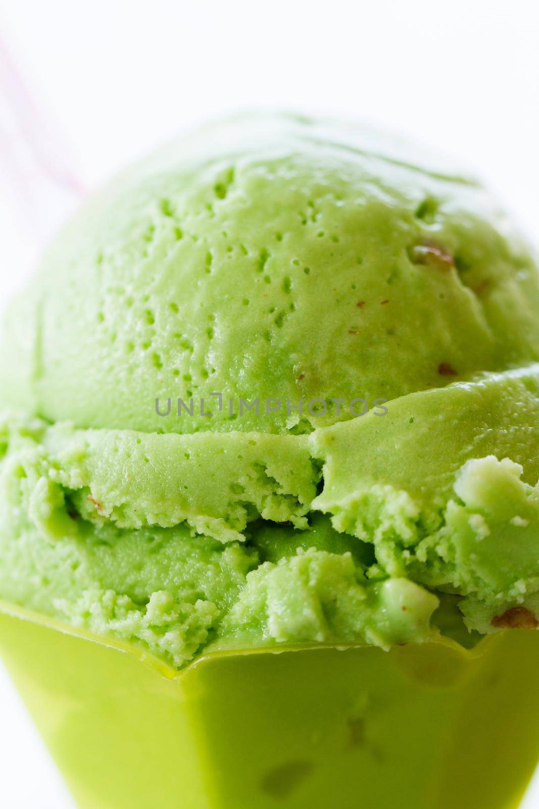 Green gelato in green plastic cup.