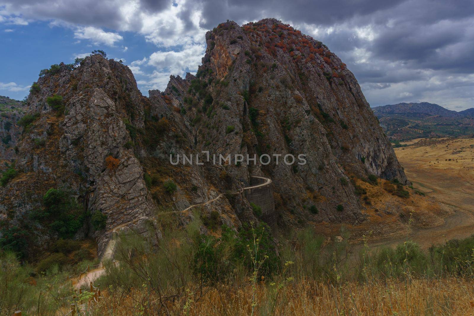 mountain landscape with a road leading to the dam of los caballeros in montejaque , malaga, spain with dramatic cloudy sky