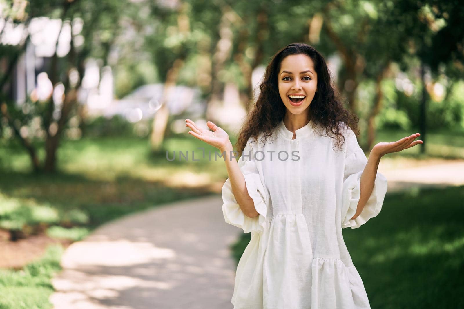 Admiring curly-haired brunette girl with raised hands. High quality photo