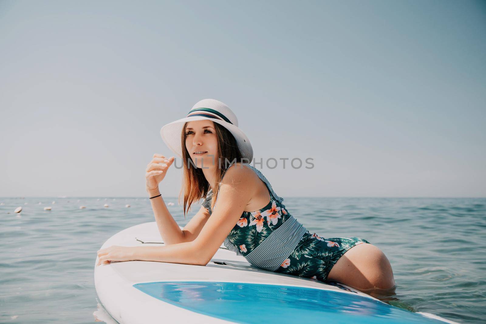 Happy young woman in swimsuits doing yoga on sup board in calm sea, early morning. Balanced pose - concept of healthy life and natural balance between body and mental development