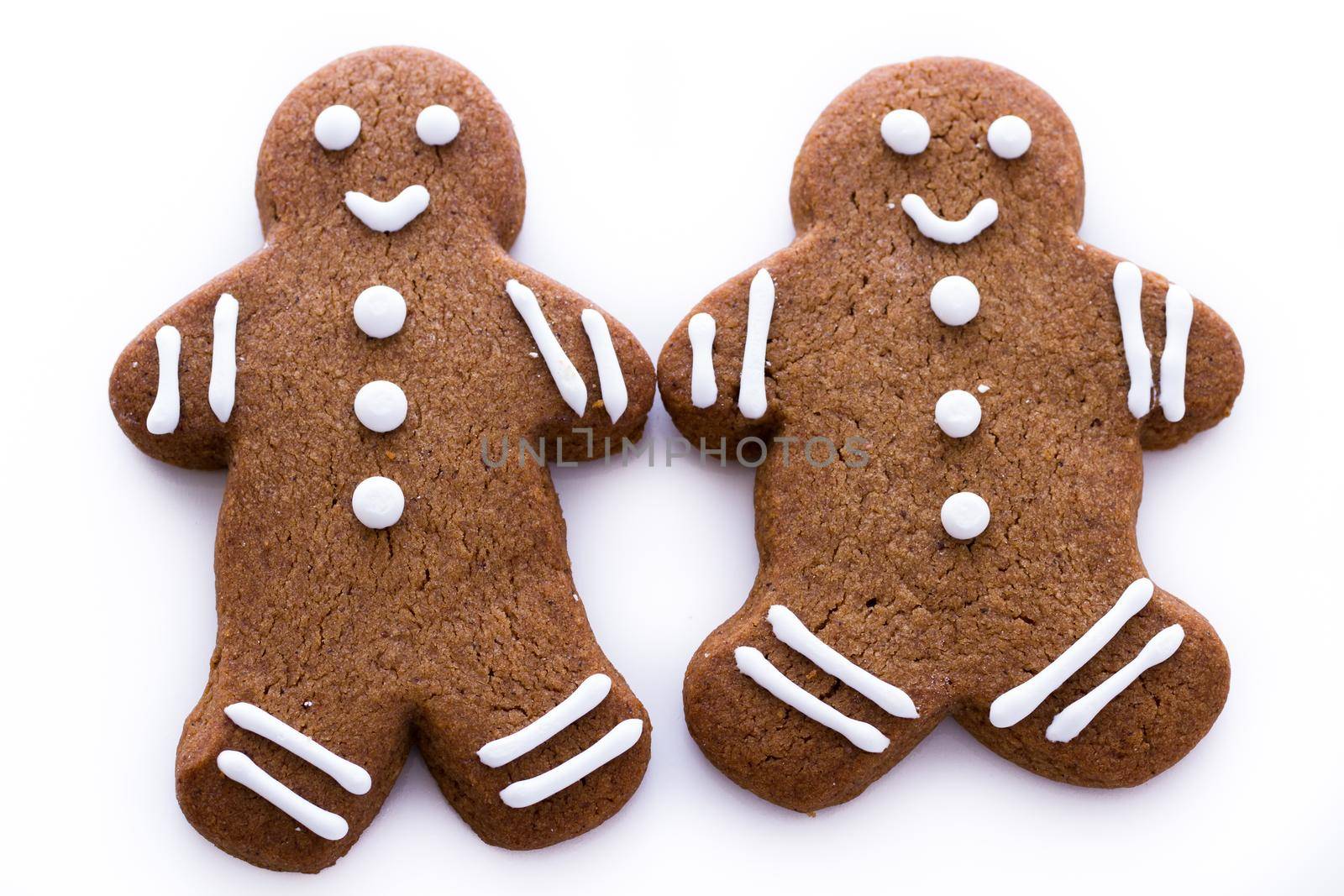 Homemade gingerbread cookies decorated with white icing on white background.