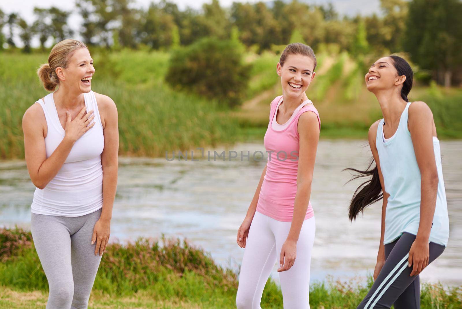 Laughing with the yoga ladies. a young woman in an outdoor yoga class. by YuriArcurs