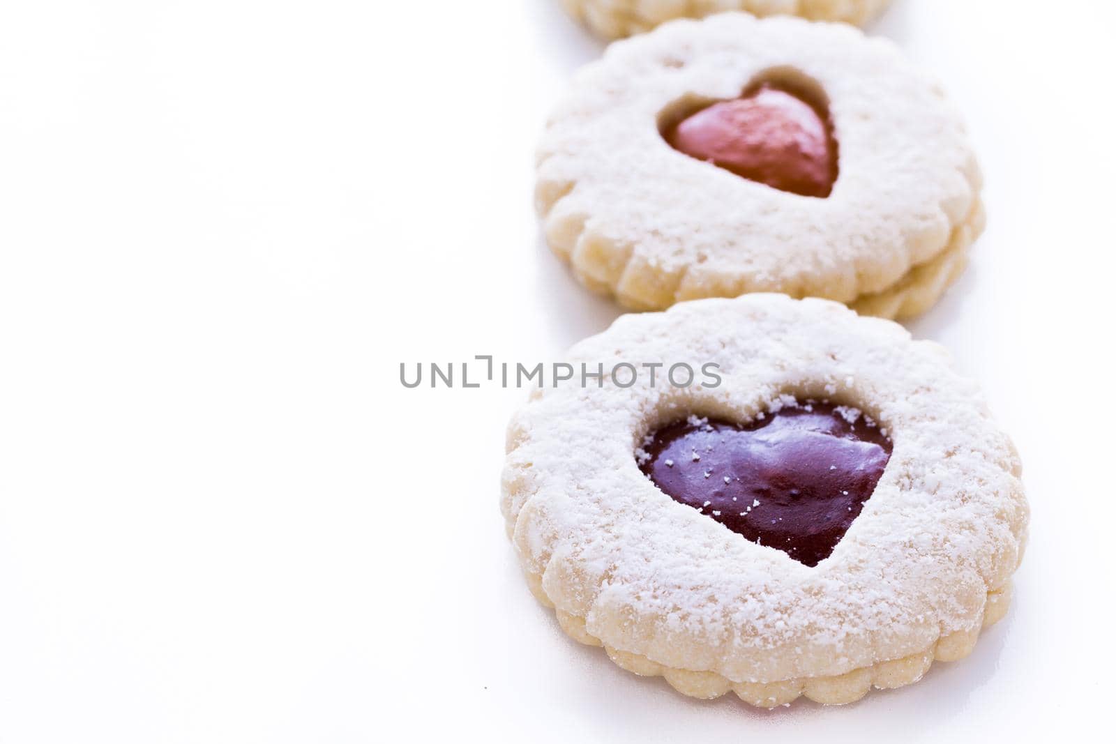 Linzer Torte cookies on white background with powdered sugar sprinkled on top.