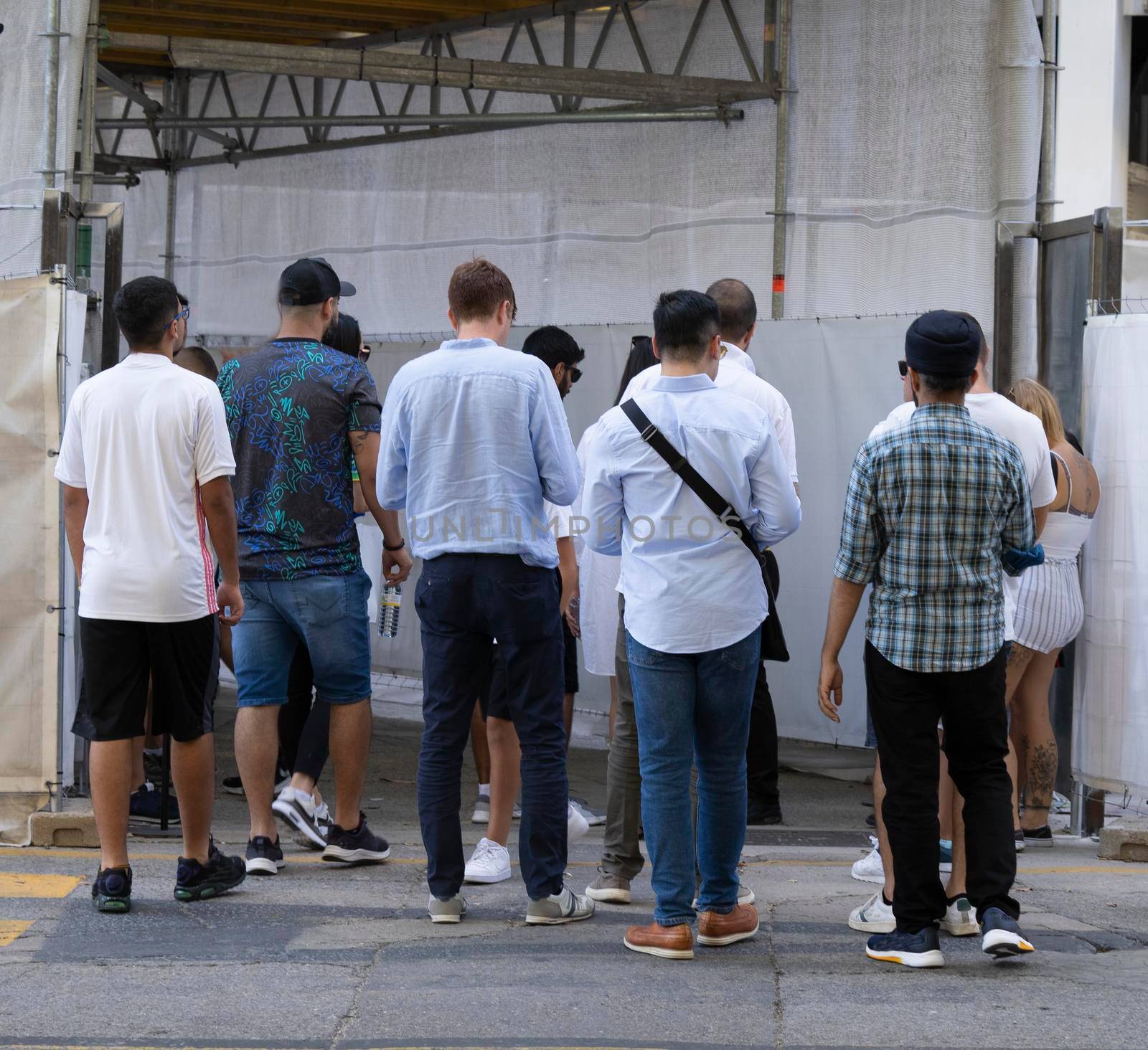 Rear view of multiethnic people walking surrounded by scaffold in a city by papatonic