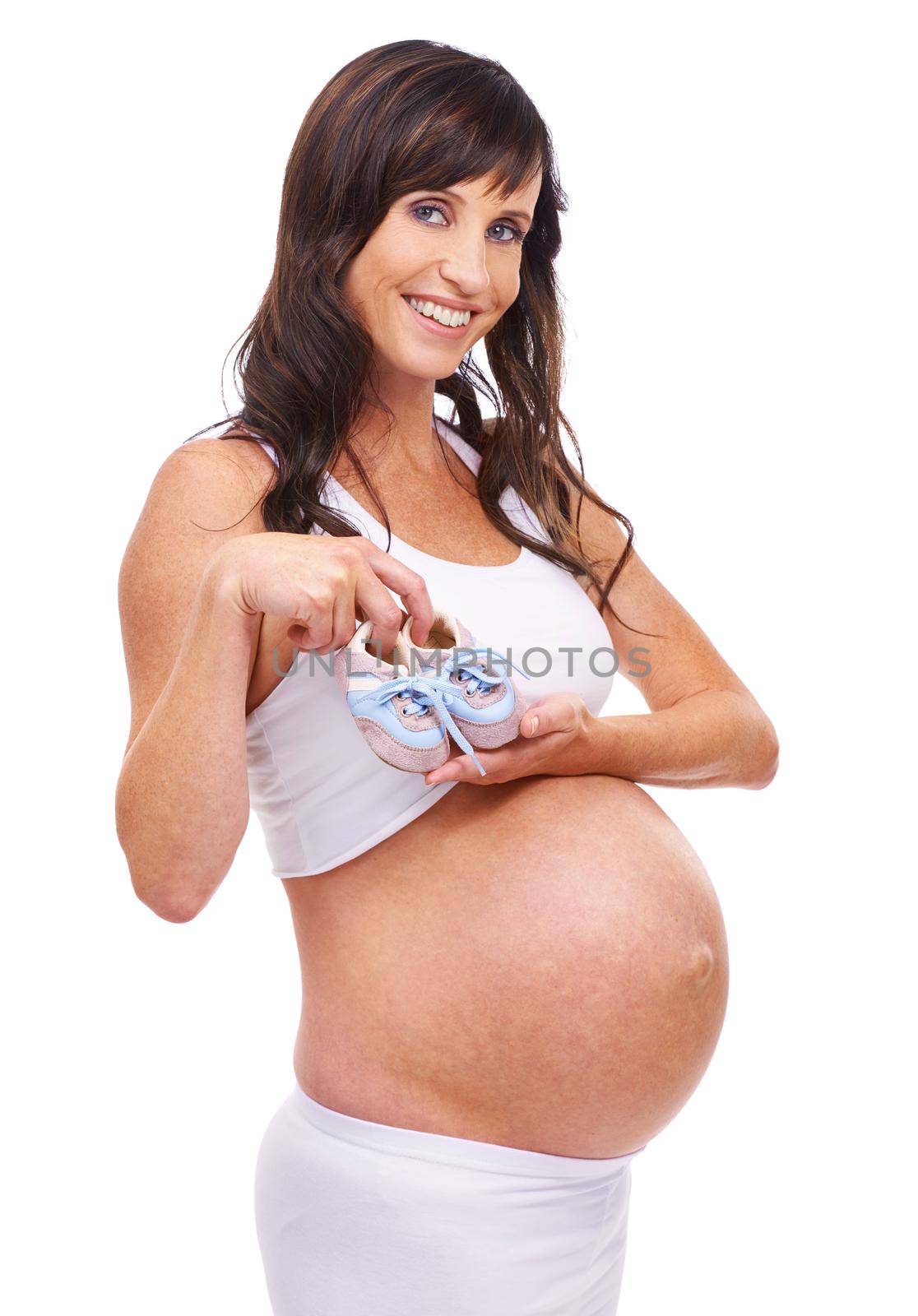 Getting prepared for the new arrival. A pregnant mother holding a pair of baby shoes in front of her belly