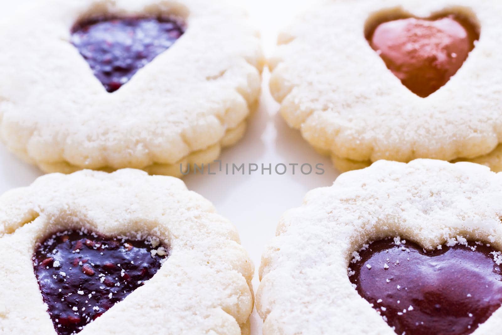 Linzer Torte cookies on white background with powdered sugar sprinkled on top.