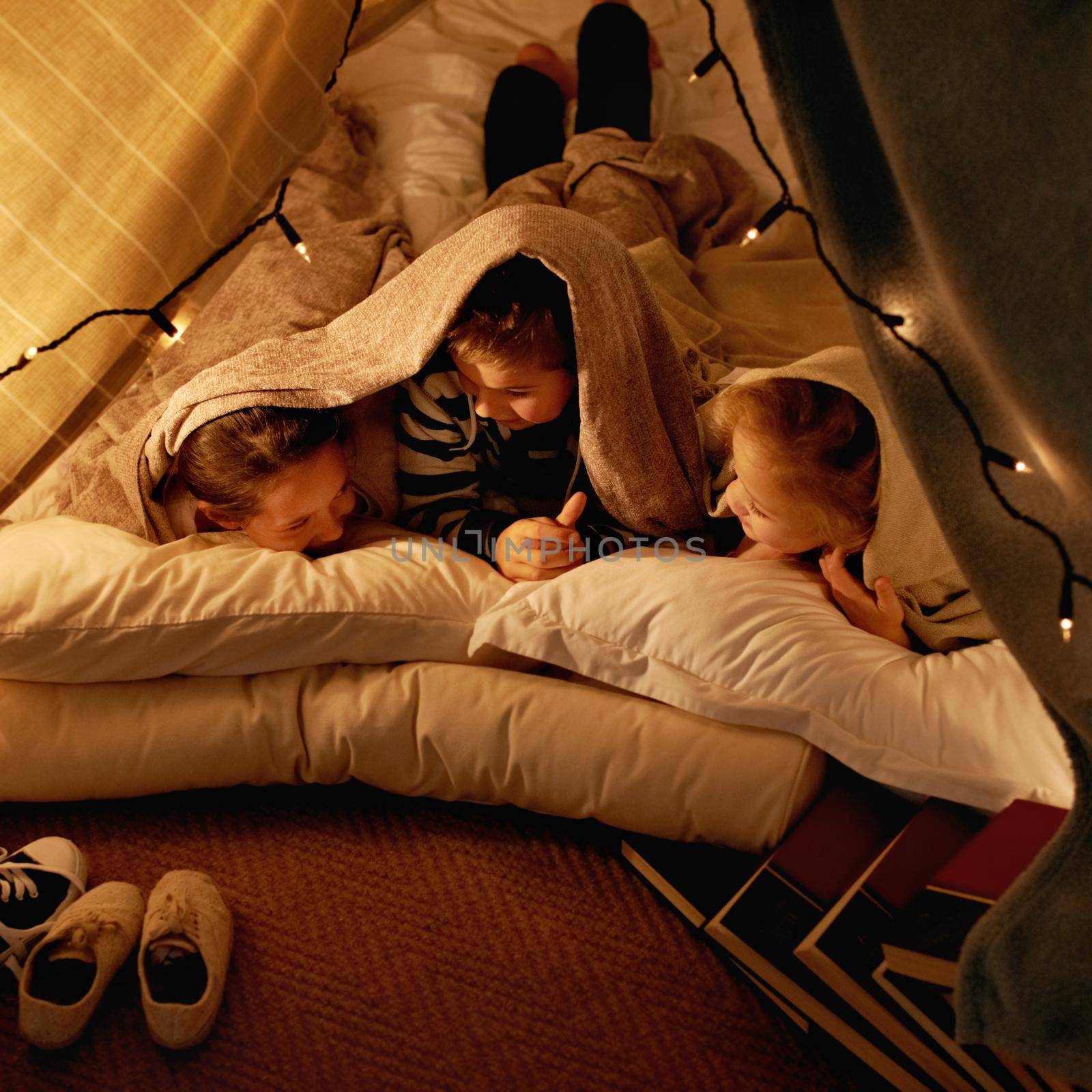 Were never going to sleep. three young children playing in a tent together. by YuriArcurs
