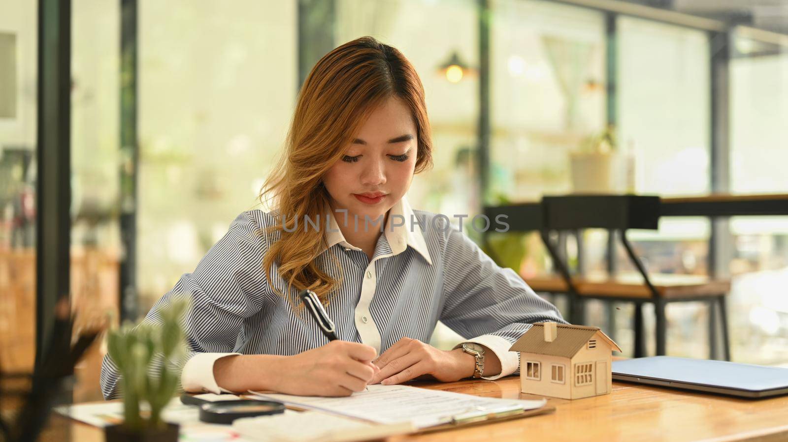 Concentrated female financial advisor preparing contract document for client on her working desk.