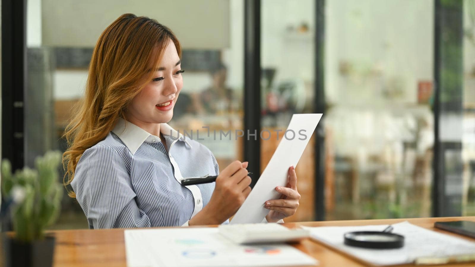 Professional female accountant examining the numerical data on financial document at her workplace.