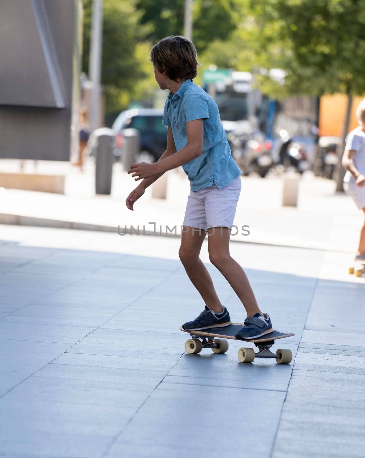 Young active elegant stylish kid balancing on a skateboard in Madrid city centre.