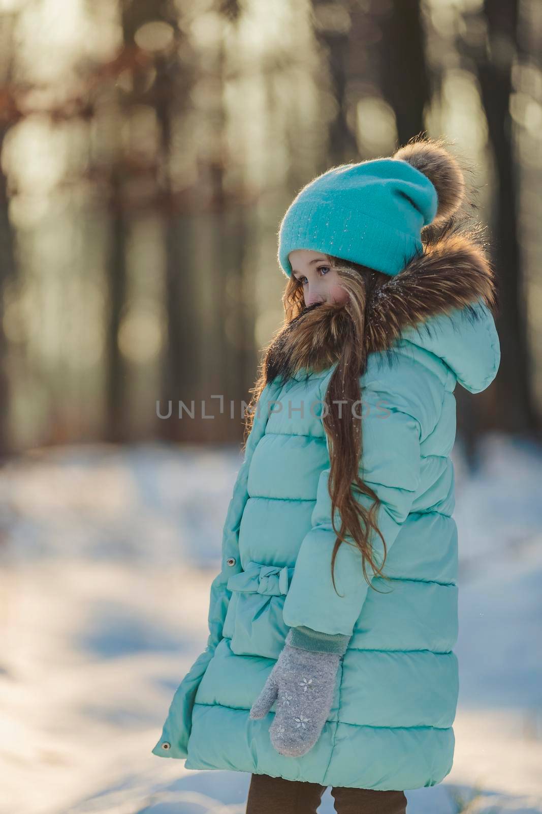 girl in a turquoise squat and a hat in a winter forest, shot vertically