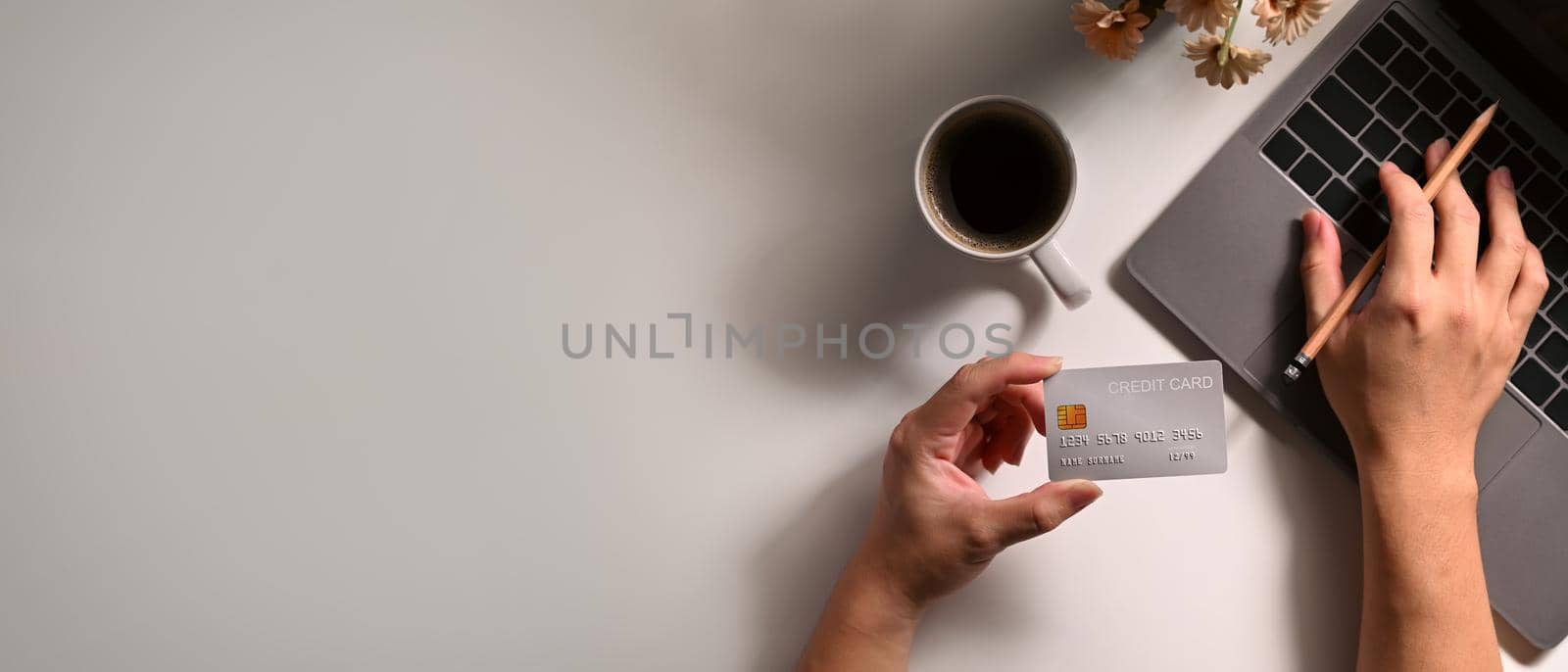 Overhead view of woman holding credit card and making payment on internet via laptop. Online shopping, e-commerce concept.