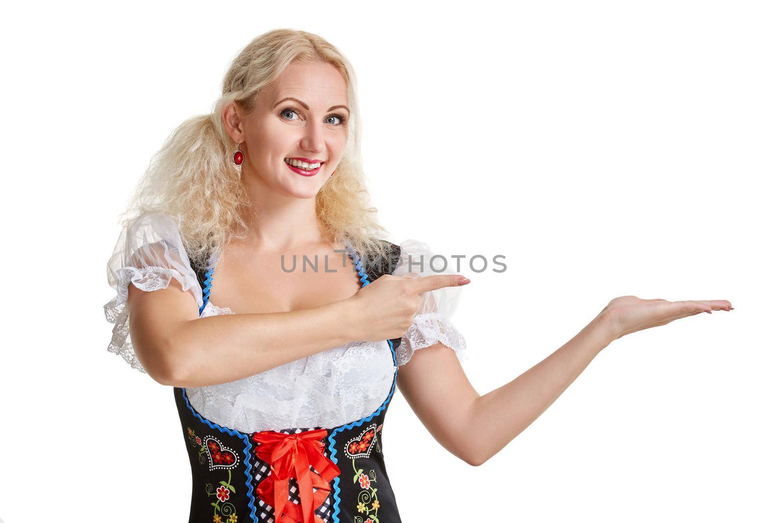 Beautiful young blond girl in dirndl drinks out of oktoberfest beer stein. Isolated on white background. pointing finger and smiling. copyspace desing concept