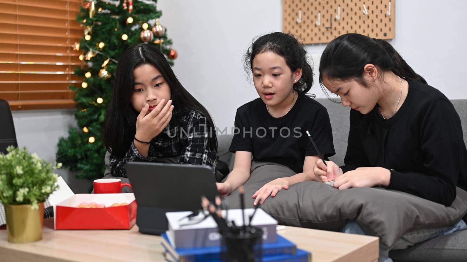 Young asian girls studying online at home together. by prathanchorruangsak