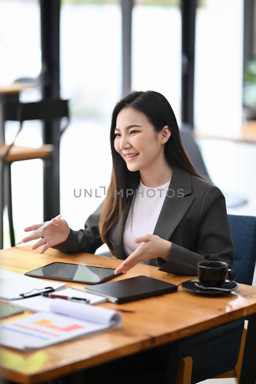 Confident businesswoman sitting in modern office and using digital tablet. by prathanchorruangsak