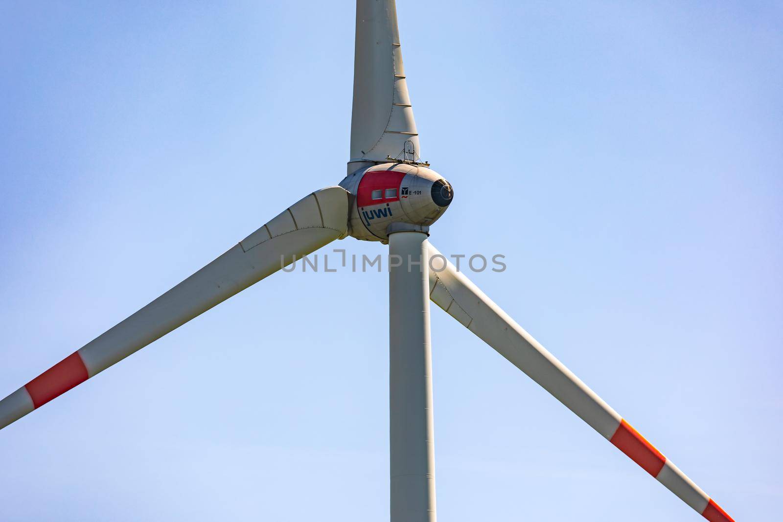 A close-up of a wind turbine with three huge rotor blades isolated against a blue sky