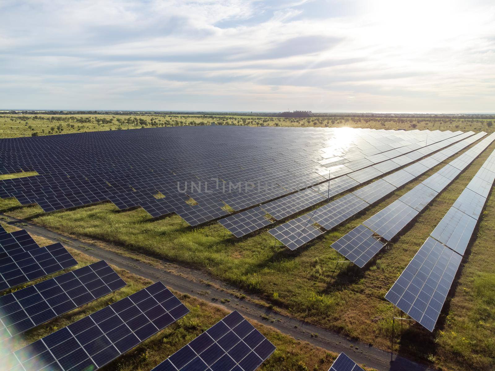 Aerial top view of a solar panels power plant. Photovoltaic solar panels at sunrise and sunset in countryside from above. Modern technology, climate care, earth saving, renewable energy concept. by panophotograph