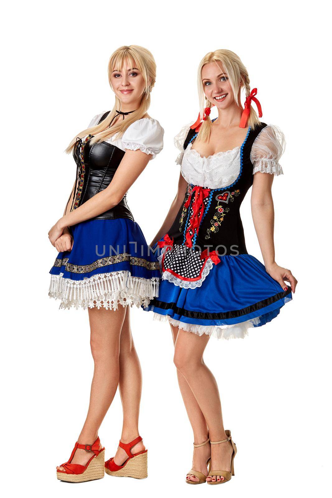 A full length portrait of two beautiful women in a traditional costume isolated on white. Oktoberfest by nazarovsergey