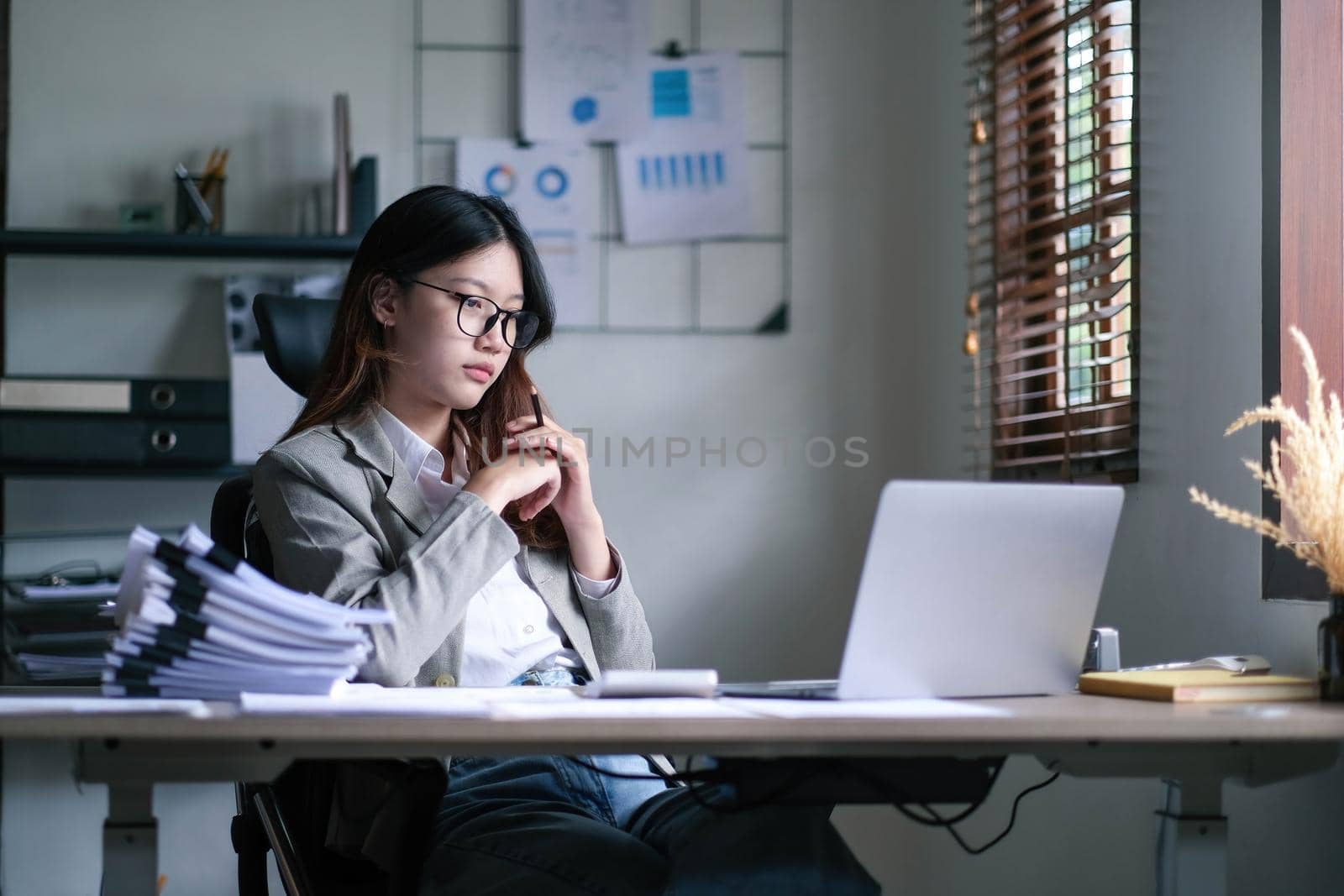 Young Asian woman feeling migraine head strain. Tired, Overworked businesswoman financier while working on laptop computer in office..