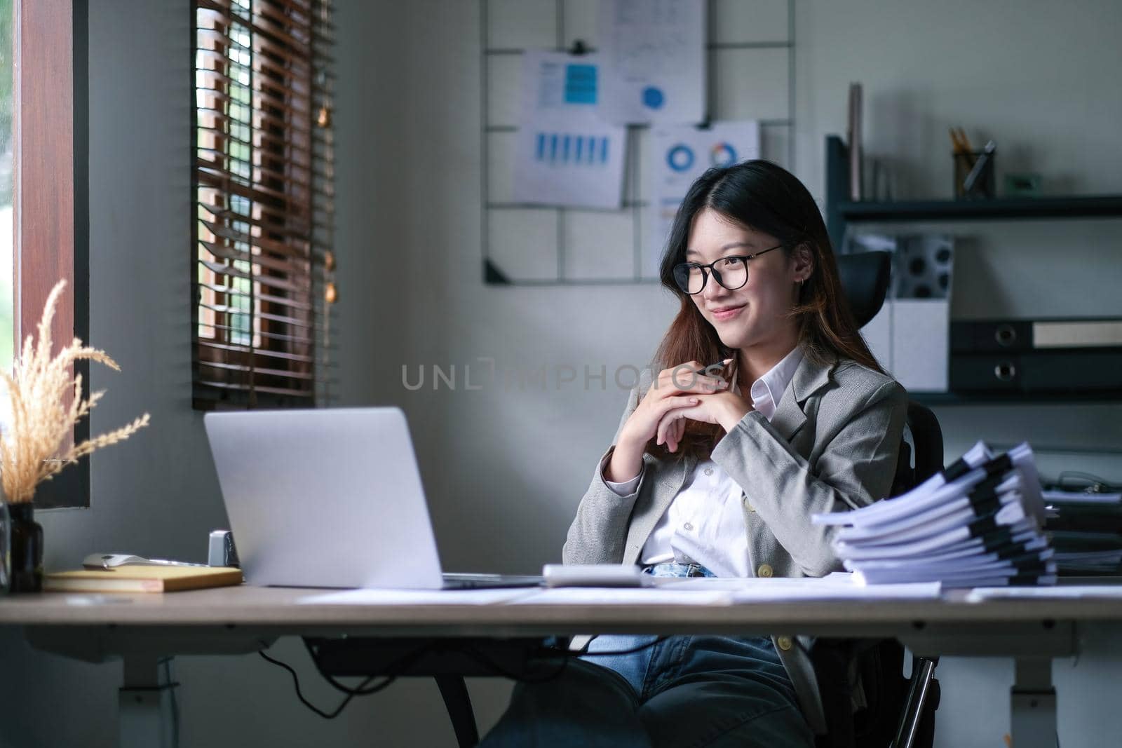 Asian Businesswoman Using laptop computer and working at office with calculator document on desk, doing planning analyzing the financial report, business plan investment, finance analysis concept..